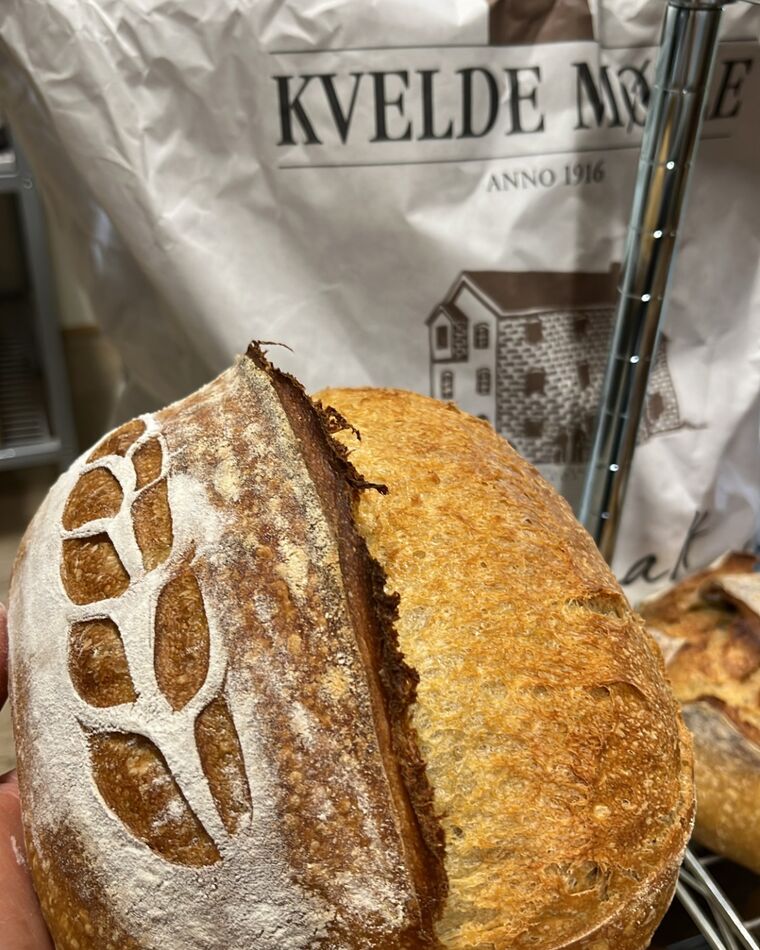 Surdeigsbrød med aksmønster foran en melsekk fra Kvelde Mølle.